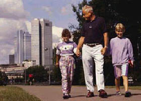 Man and two children walking with a city in background